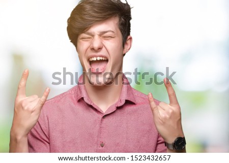 Young handsome business man over isolated background shouting with crazy expression doing rock symbol with hands up. Music star. Heavy concept.