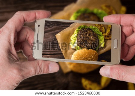 Man taking photo of Grilled beef hamburber with potato on wood table