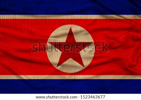 photo of the national flag of north korea on a luxurious texture of satin with waves, folds and highlights, close-up, copy space, travel concept, economy and state policy