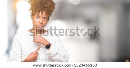 Beautiful young african american woman wearing winter sweater over isolated background In hurry pointing to watch time, impatience, upset and angry for deadline delay