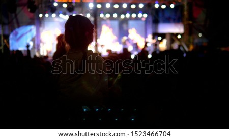 blurred background, silhouettes of fans. rock concert in the evening. people in the crowd raise their hands and applaud.