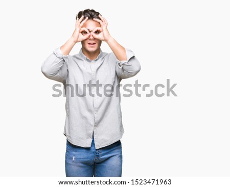 Young handsome man wearing glasses over isolated background doing ok gesture like binoculars sticking tongue out, eyes looking through fingers. Crazy expression.