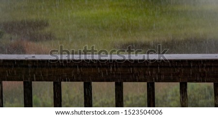 Pouring rain on a deck railing. Water caught splashing up using slow shutter speed.