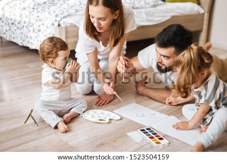 little baby holding a cup with water while having painting lessons with parents . close up photo