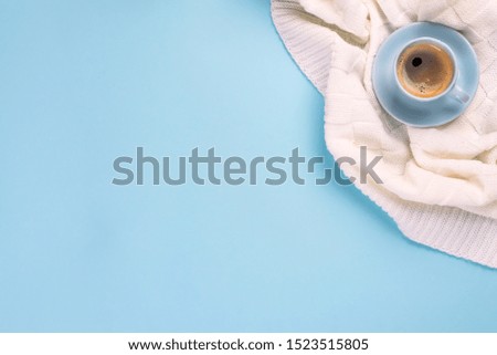 Blue cup of coffee on plaid over the blue paper background with copy space, flat lay. Cozy winter