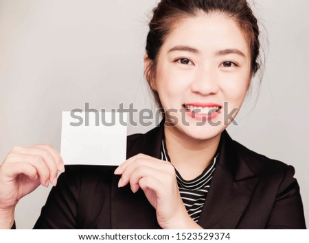 Young beautiful asian business woman wore black suit,Holding an empty white card for text