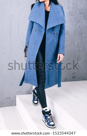 Studio photography of demi-season clothing. Young adult girl in an elegant coat on a gray background. Promotional women's coat. woman in a stylish autumn-spring coat. Casual wear.