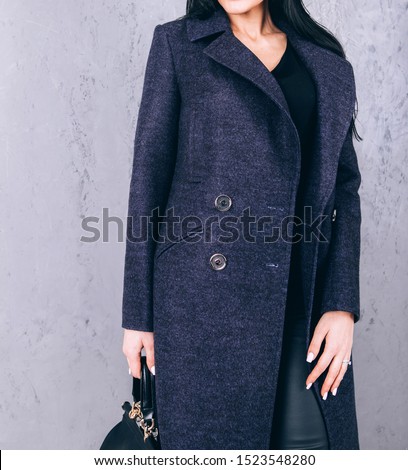Detail of outerwear close-up. Studio photography of demi-season clothing. Young adult girl in an elegant coat on a gray background. Promotional women's coat. woman in a stylish autumn-spring coat.