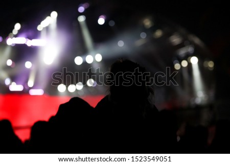 Silhouettes of people at a rock concert as background. Bokeh