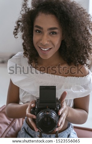 Good-looking woman holding a big professional camera before taking a picture