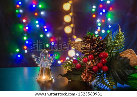 Christmas tree branch with cones and rowan berry and gold ball like angel are on the shiny table/background. There are different colors lights on the background. Merry Christmas. Happy New Year 2020.