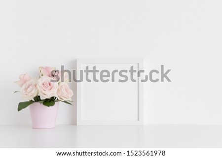 White square frame mockup with pink roses in a pot on a white table.