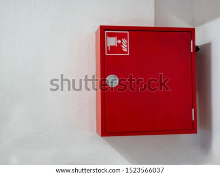 Wall mounted fire water hoses and fire fighting equipment on red cabinet