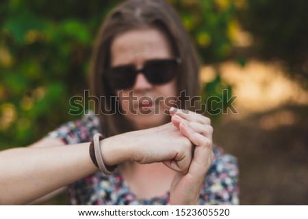 Beautiful young woman holding her fist on her palm outdoors - Pretty girl making hand gestures in sign of strength in the park - Concept image for woman power