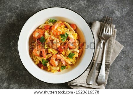 Paella or risotto with chicken breast, shrimp tails, carrots, onions, cherry tomatoes, white wine and chicken stock. Top view. 