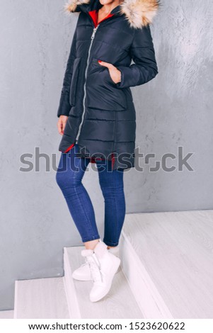 Detail of outerwear close-up. Winter jacket. Studio shooting demi-season clothing. Jacket with faux fur. young adult girl in elegant winter clothes on a gray background.