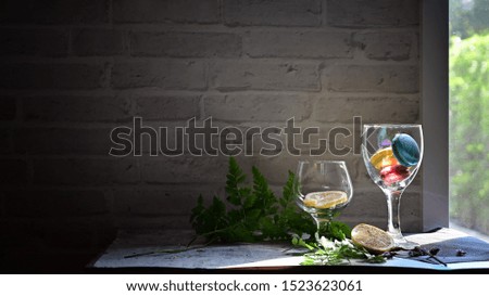 Macaron and lemon in wine glass with decorative table with windows light.