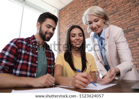 Female notary working with young couple in office