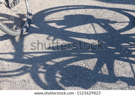 Shadow and wheel of a bicycle on the pavement. Abstract background. The concept and promotion of a healthy lifestyle among the population. Sports event bike ride. Cycling.