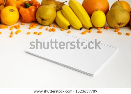 Fresh autumn yellow and orange vegetables and fruits and notebook on white background, top view. flat lay. autumn background.