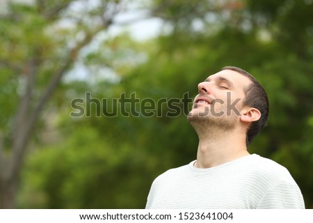 Happy man breathing deeply fresh air in a forest with green trees in the background Royalty-Free Stock Photo #1523641004