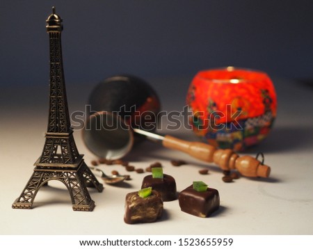 Chocolates with gold sprinkles and various items on a light background / Chocolates in gold sprinkles / Chocolates lie on a light background with a red candlestick