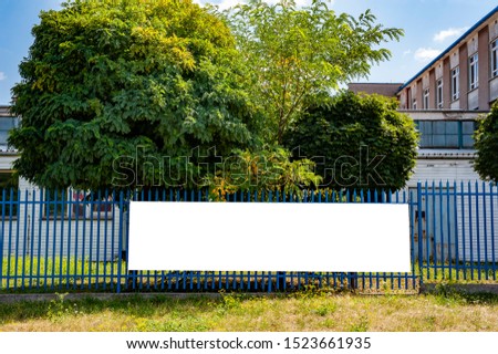 Blank white banner mockup mounted on the fence of industrial building