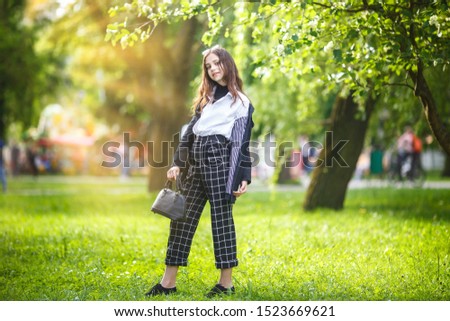 portrait of little beautiful stylish kid girl in city park on green forest background