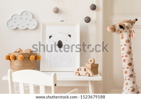 Modern and design scandinavian interior of kidroom with white desk, armachir, mock up poster frame, natural basket, toys, teddy bear, plush toys and cute children's accessories. Stylish home decor.