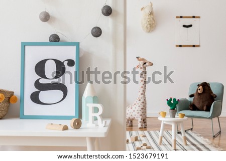 Modern and design scandinavian interior of kidroom with white desk, armachirs, mock up poster frame, natural basket, toys, teddy bear, plush toys and cute children's accessories. Stylish home decor.
