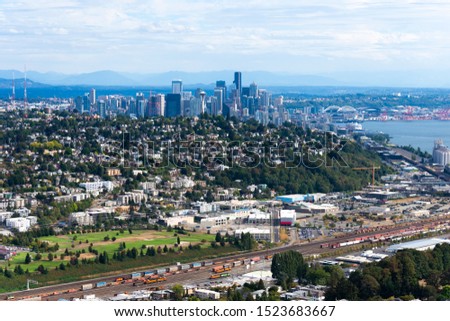 Seattle aerial overview from North showing a golf course, railway lines, residential houses, city center, water front and sports stadiums.