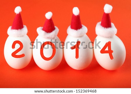 Happy New Year 2014! Four eggs in Santa's hats isolated on red