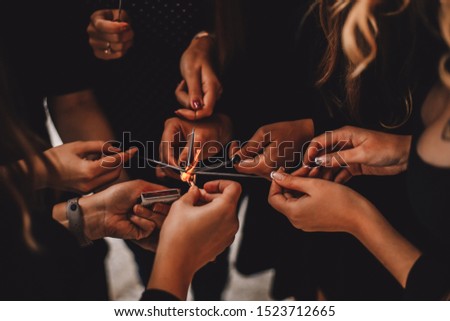 Colorful picture of women hands trying to fire up Bengal lights with safety matches on a windy day. Cropped bengal fire sticks, sparkling, burning, elegant classy ladies hands holding fire-sticks.