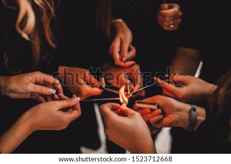 Colorful picture of women hands trying to fire up Bengal lights with safety matches on a windy day. Cropped bengal fire sticks, sparkling, burning, elegant classy ladies hands holding fire-sticks.