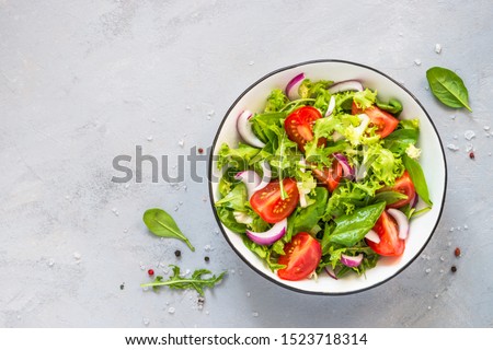 Green vegan salad from green leaves mix and vegetables. Top view on gray stone table. Royalty-Free Stock Photo #1523718314