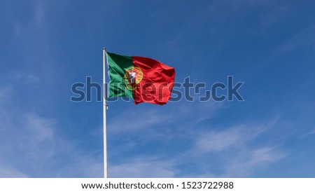 Beautiful large Portuguese flag waving in the wind against blue sky. Portuguese Flag Waving Against Blue Sky. Flag of Portugal waving, against blue sky 