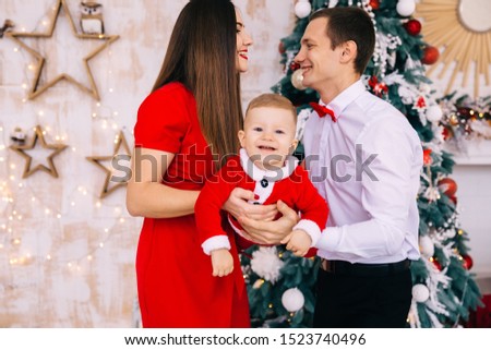 parents and toddler looking at camera and smiling. Christmas tree in room. baby flying.