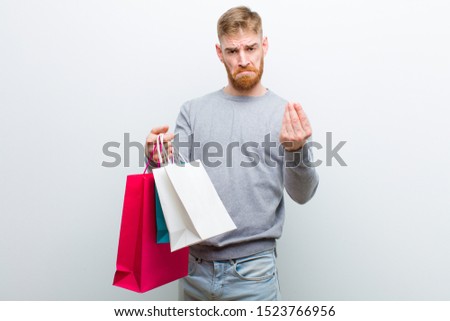 young red head man with shopping bags against white background