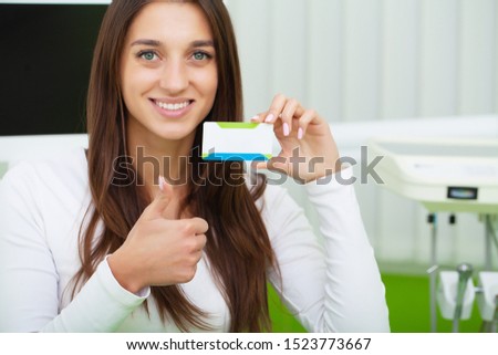 Dental care. Woman at dental clinic holding blank business card