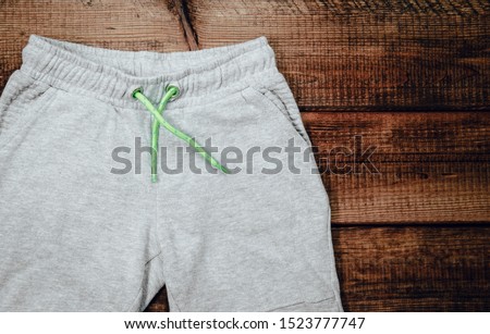 Top view of gray sweatpants on wooden background. Children's sweatpants with visible two legs. Royalty-Free Stock Photo #1523777747