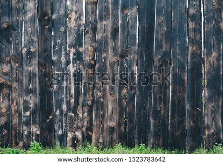 Photo of a black charred wooden fence made of boards with green grass in high resolution