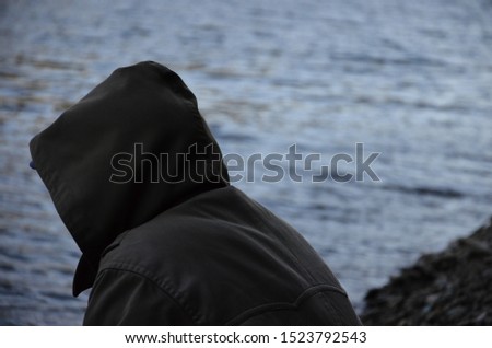Mysterious man wearing a hood on the lake