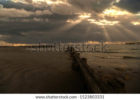 Very dark and moody photo of a beach scene - background clouds almost looks like there is a sky fire