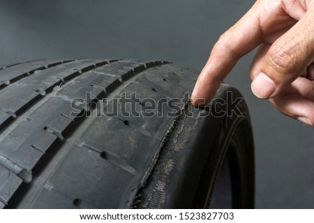 Finger pointing to damage on tire tread. Tire tread problems by tire pressure improper, Wheel alignment Royalty-Free Stock Photo #1523827703