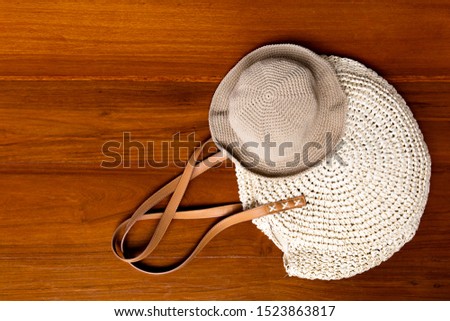 Beautiful knitted handcraft women bag and hat in global warming concept on wood pattern background. Photo from top view with copy space