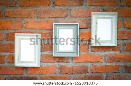 Many picture frames hung on the brick wall to decorate the place for beauty.