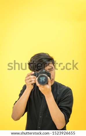 Young Professional photographer is taking picture in modern studio with photo studio background.