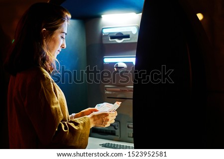 a young woman getting money from an atm machine