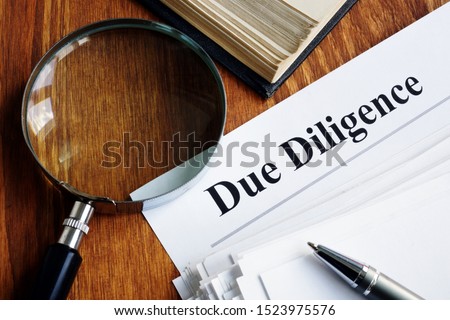 Due Diligence concept. Stack of documents and magnifying glass. Royalty-Free Stock Photo #1523975576