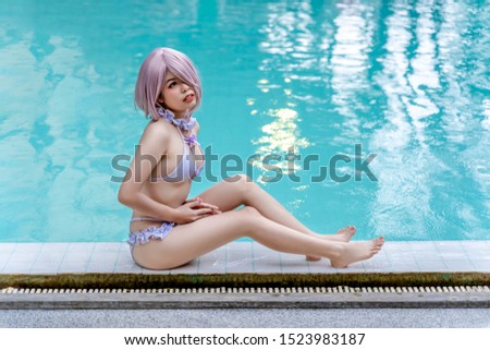 Young cute girl in bikini sitting near swimming pool